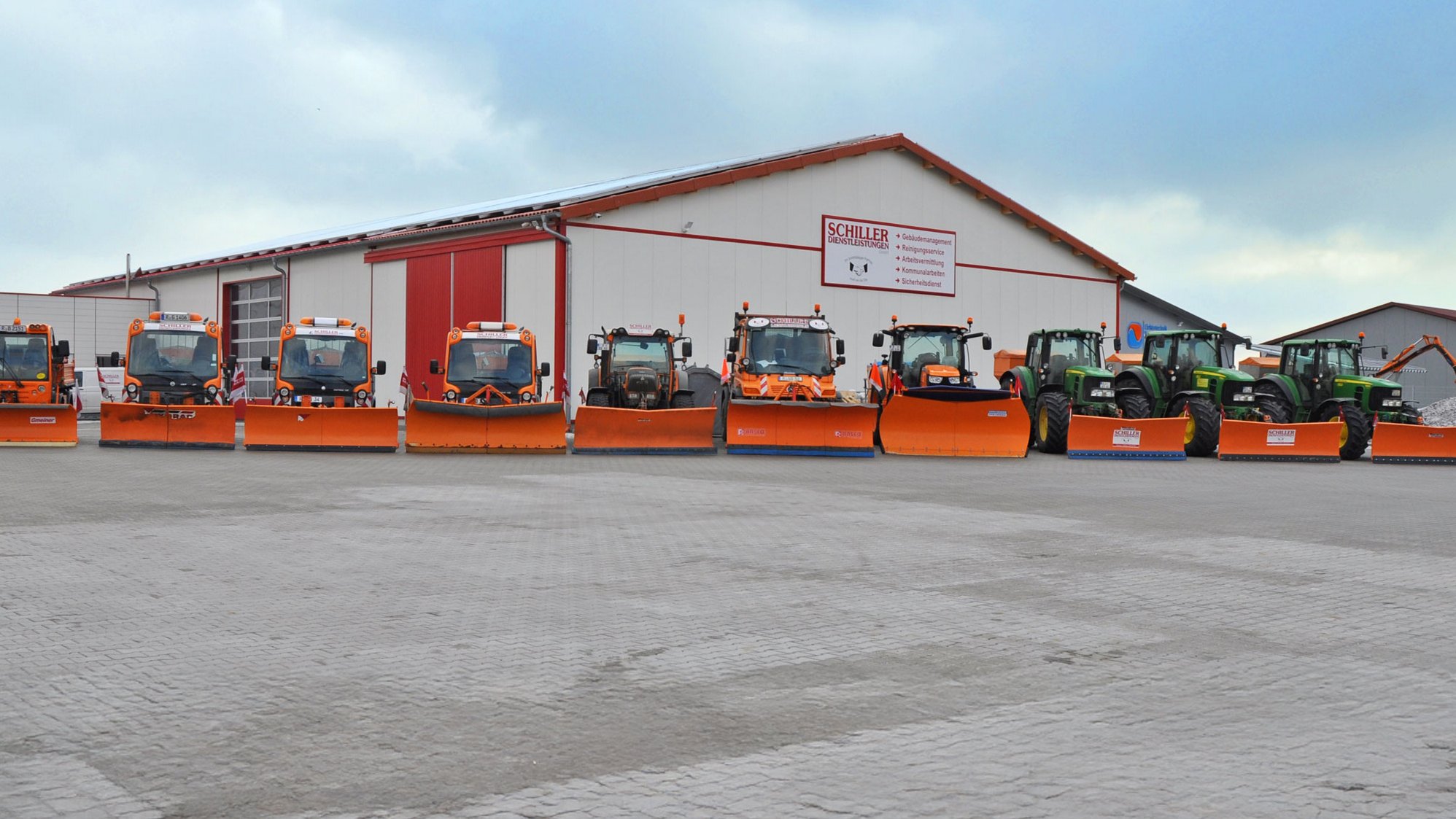 Winterdienst mit Schneeräumung und Streudienst in Regensburg Maschinen der Schiller Service GmbH stehen nebeneinander vor dem Firmengebäude